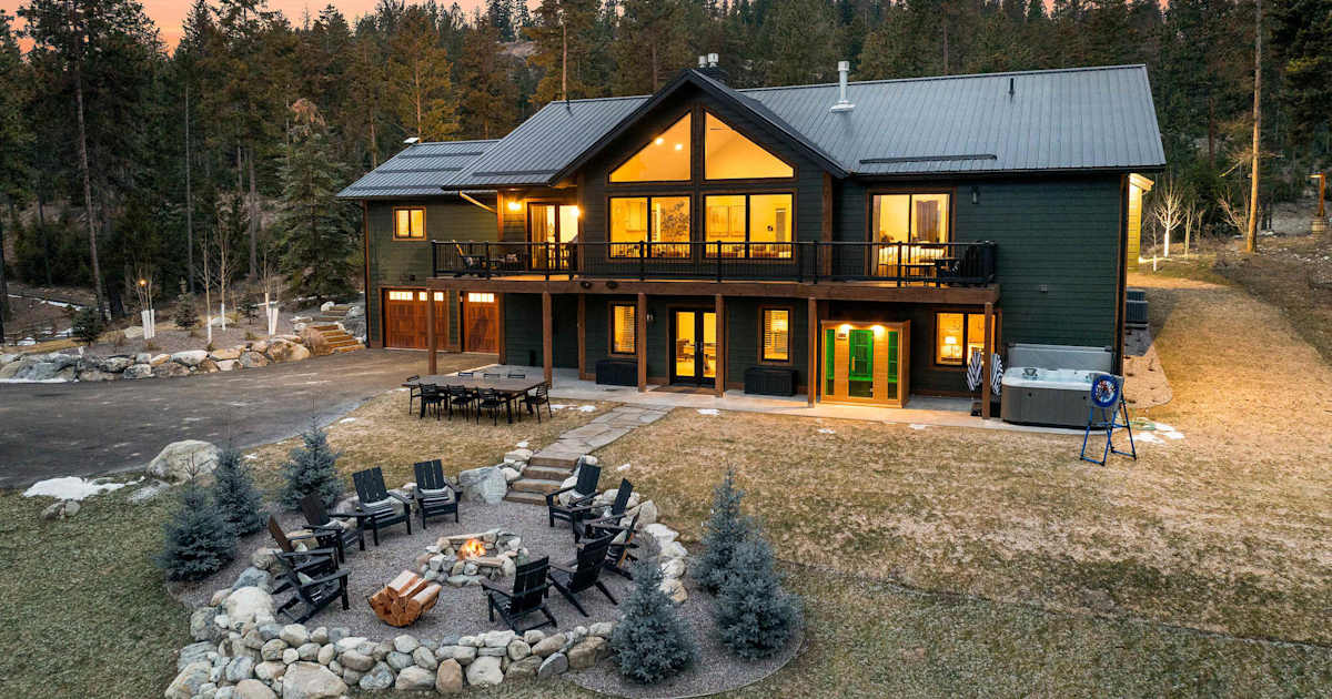 The Tamarack — rear view of multi-level lodge featuring fire pit seating, patio, and upper deck at dusk