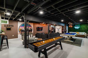 A full-scale private game room with shuffleboard, pool table, arcade machines, foosball, darts, and a custom neon sign — the best Pocono vacation rental game room, all included.