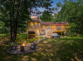 Everything you came for — fire pit, private hot tub, barrel sauna, and a spacious deck, all glowing at twilight in your own Poconos backyard retreat.