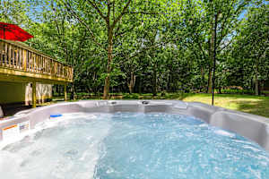 A full-size private hot tub with jets running, nestled beneath the deck and surrounded by Pocono forest — one of the most searched amenities in the region, and it's all yours.