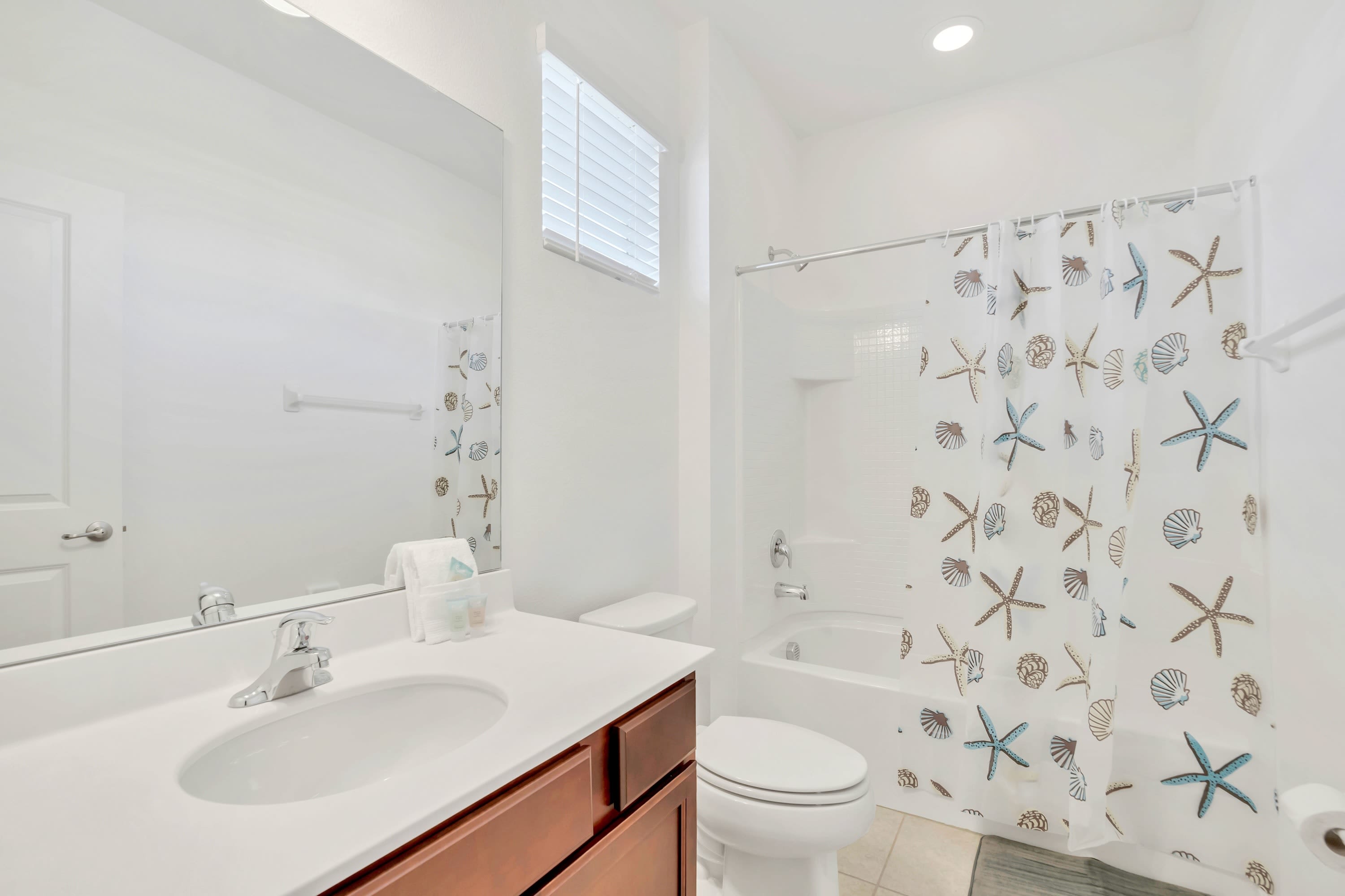 A pristine bathroom sink vanity stocked with freshly rolled bath towels