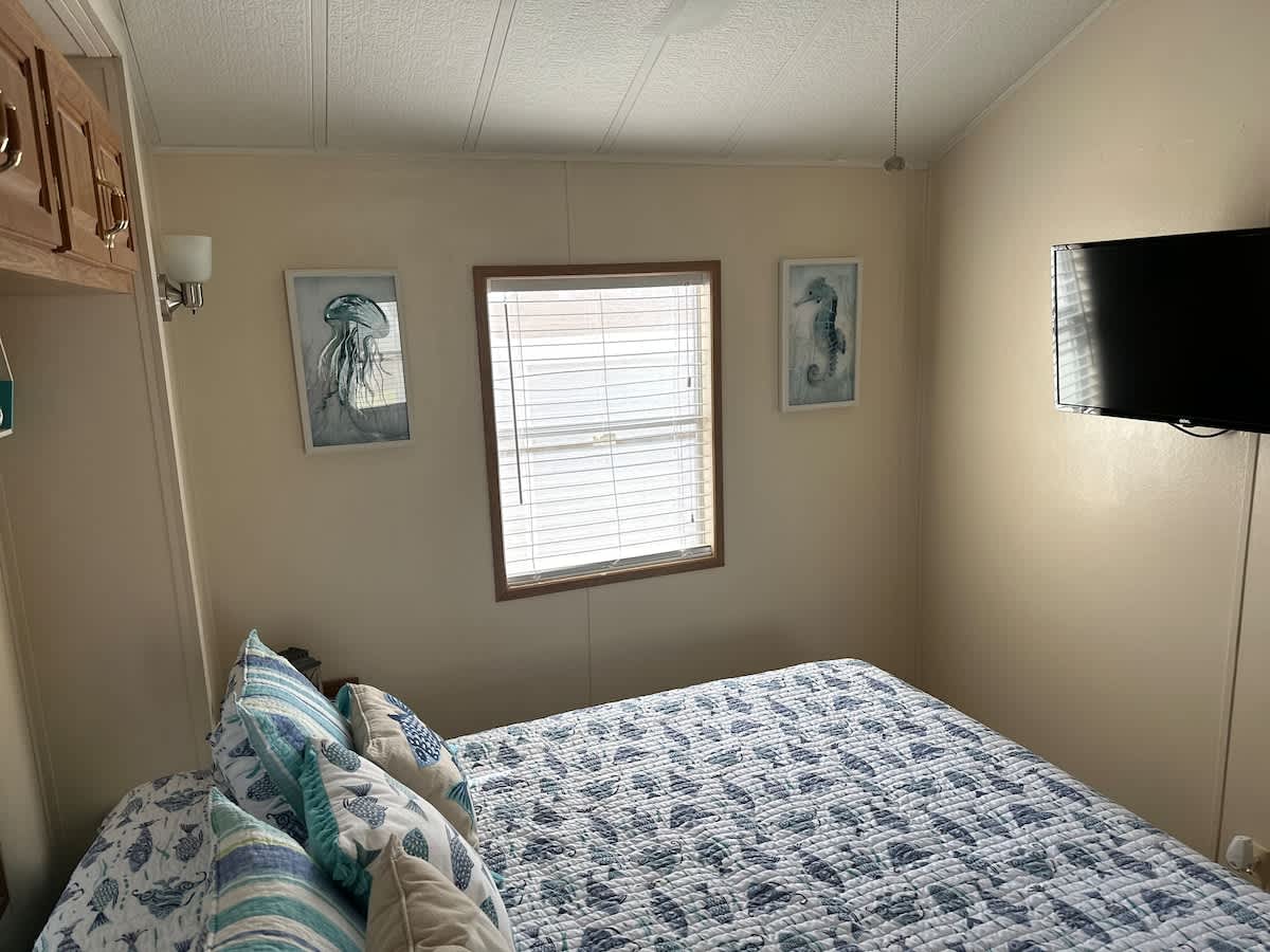 Queen bed with beach-inspired bedding décor and a TV for a restful stay.