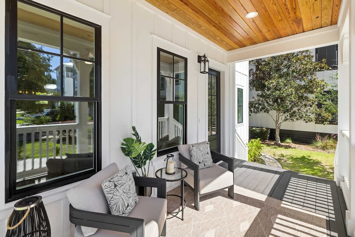 Front porch with two chairs, a small table, and a view of the yard.