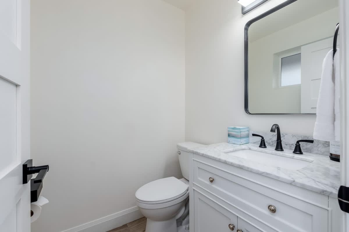 Your private bathroom features a crisp white vanity with marble countertop, modern fixtures, and fresh towels awaiting your arrival.