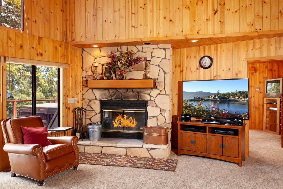 Living room with stone fireplace and TV with cable