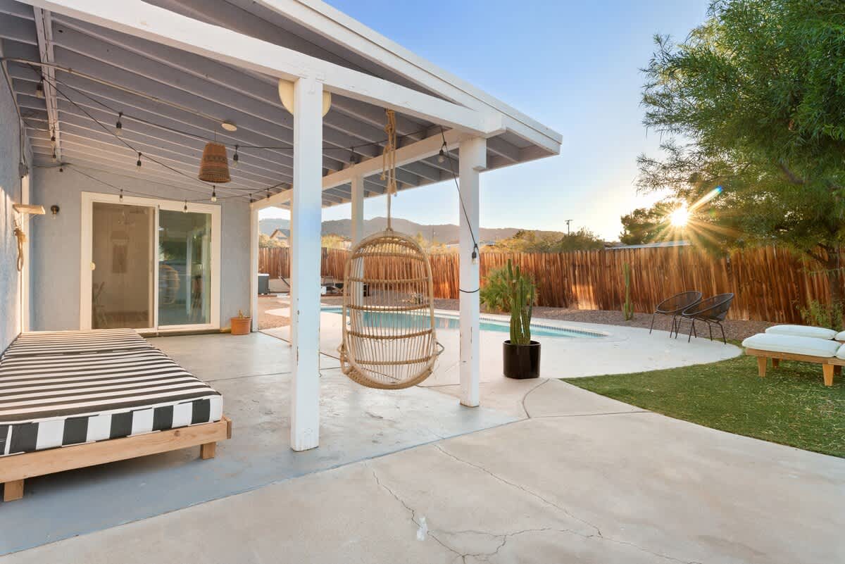 Covered back patio with hanging chair and daybed.