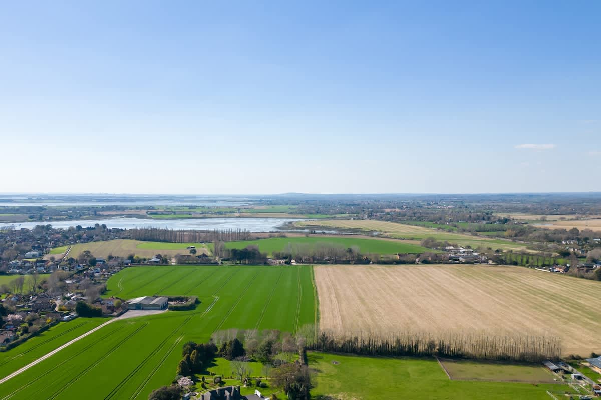 Experience stunning countryside views with this aerial photo of lush green fields, tranquil farmlands, and serene waterways. A peaceful retreat surrounded by nature, ideal for relaxing and exploring the great outdoors.
