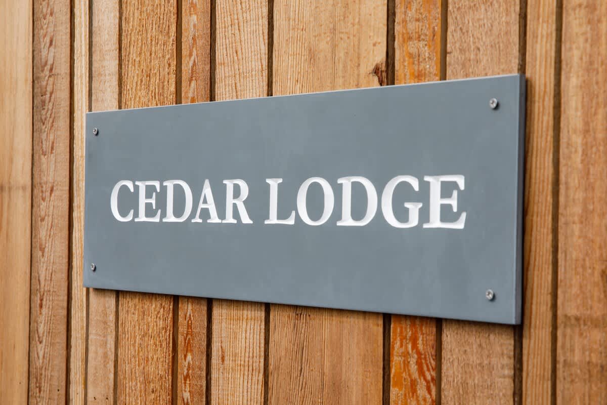 Cedar Lodge: Welcoming signage showcasing the name of this stylish countryside retreat. A perfect getaway destination offering comfort, modern amenities, and serene surroundings for an unforgettable stay.