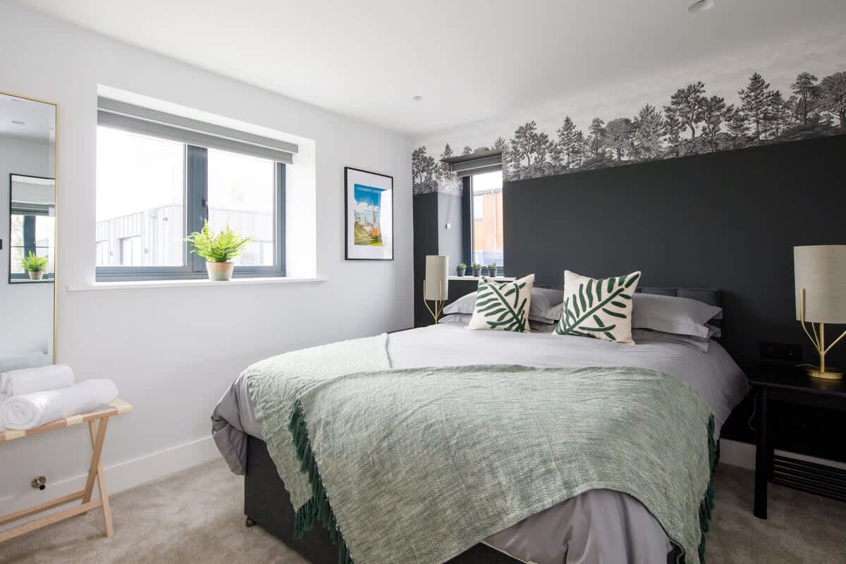 Cedar Lodge Bedroom - Chic and cozy bedroom with a king-size bed, botanical-themed decor, and blackout accents for a restful night. Features large windows, soft linens, and elegant lighting, creating a modern retreat for your stay.