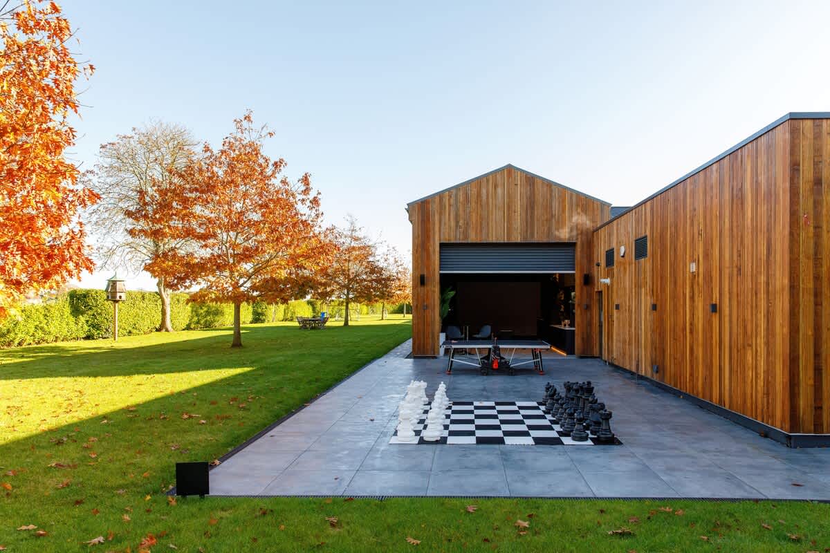 Fun-filled outdoor space featuring a life-size chess set, ping pong table, & spacious patio. Surrounded by stunning autumn foliage, this area is perfect for games & relaxation. A unique setting for making unforgettable memories with family & friends
