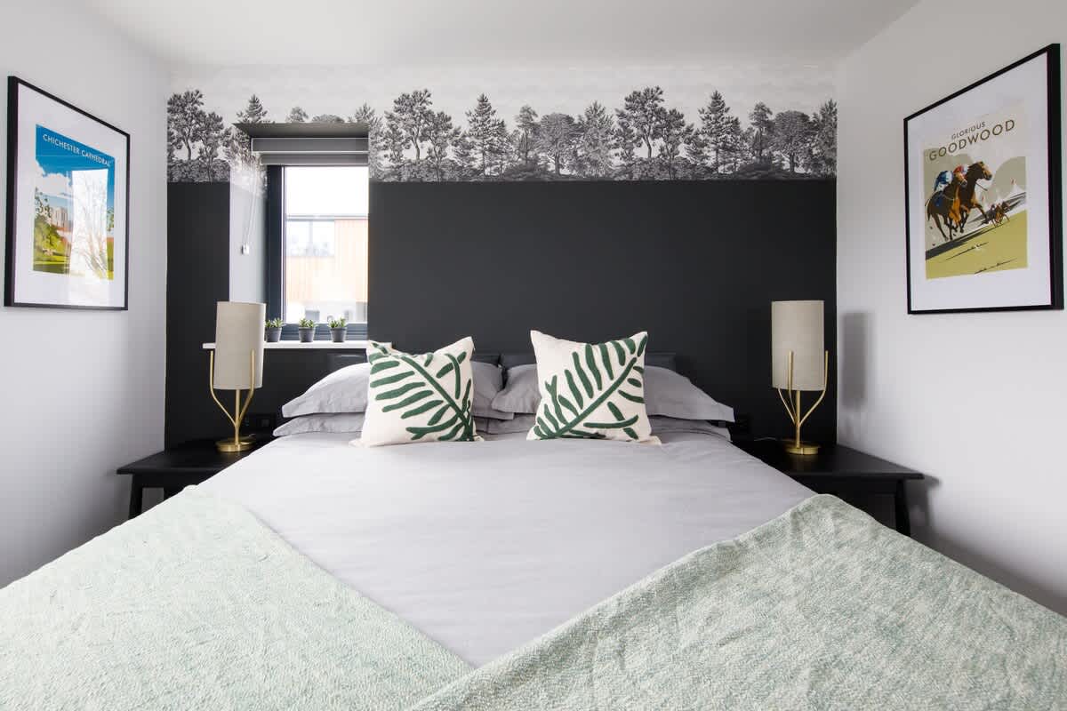 Cedar Lodge: Elegant bedroom with a king-size bed, stylish forest-themed decor, and botanical accents. Features soft lighting, cozy linens, and thoughtful design, offering a serene and comfortable space for a restful night’s sleep.