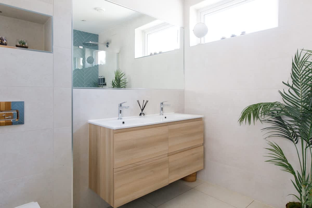 Cedar House: Bright and modern bathroom with a double sink vanity, large mirror, and natural wood accents. Features ample natural light and sleek decor, creating a luxurious and functional space for your stay