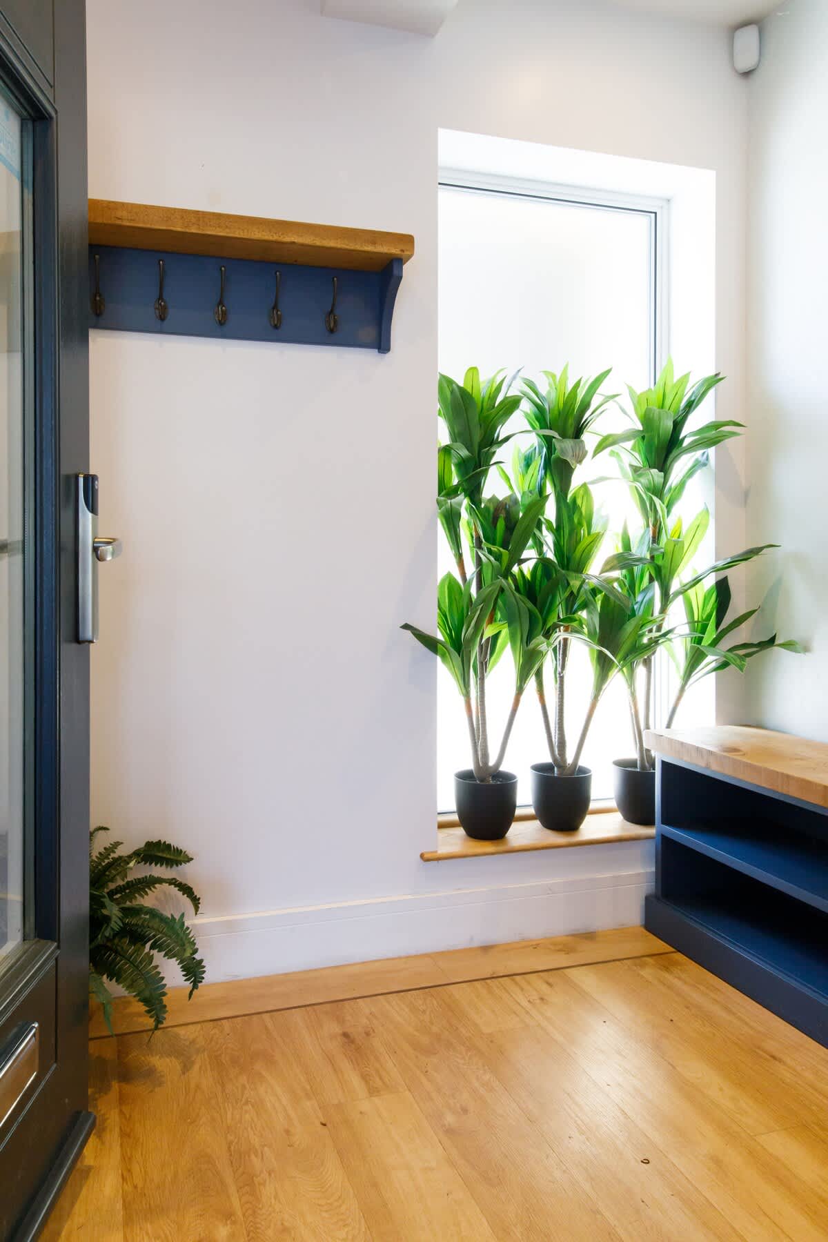 Cedar House: Bright and welcoming entryway featuring wooden floors, coat hooks, and stylish greenery. Includes a bench with storage, creating a practical yet inviting space to settle in and feel at home from the moment you arrive.