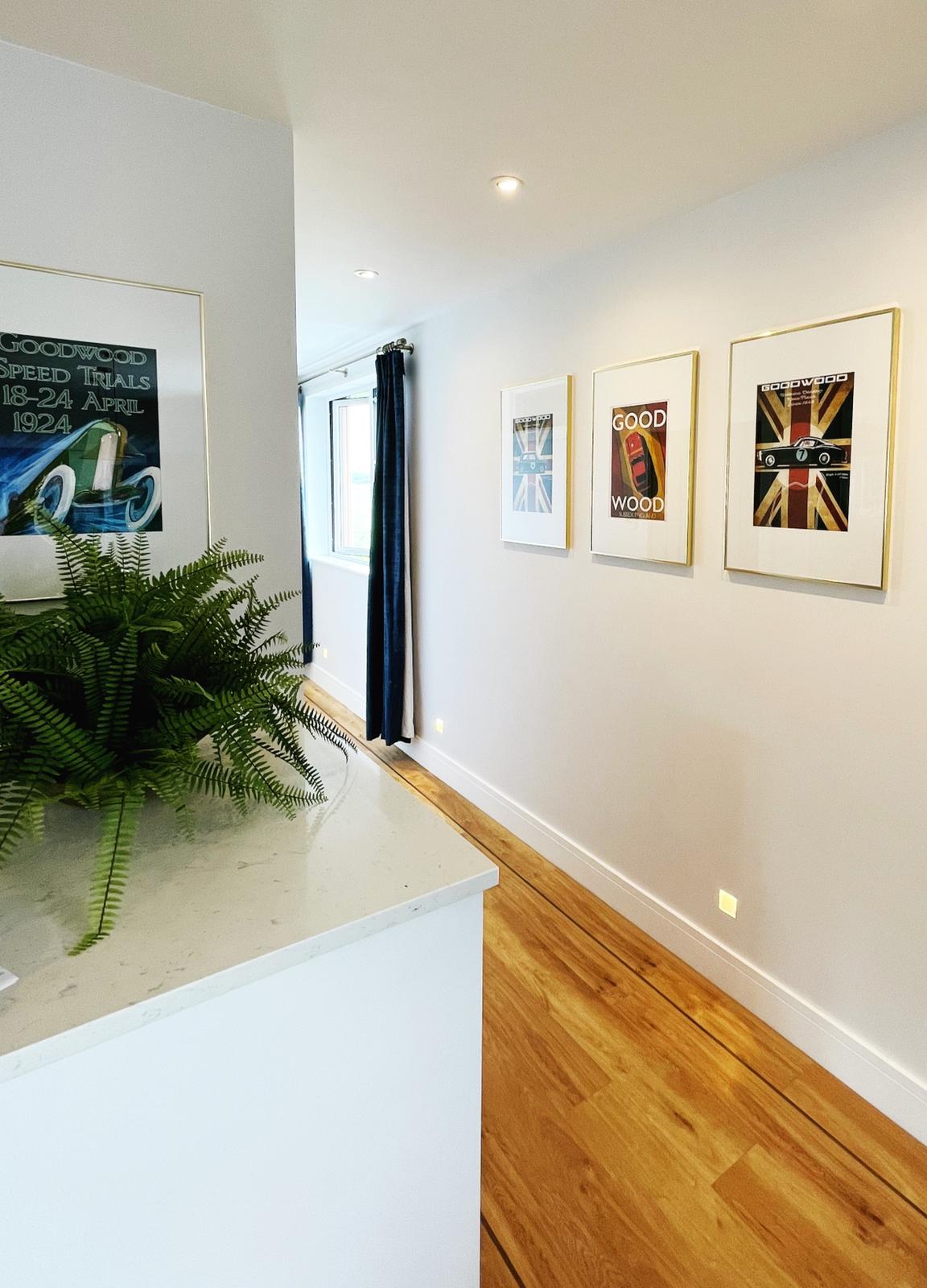 Cedar House: Bright hallway adorned with stylish Goodwood-themed artwork and elegant decor. Features natural light, hardwood flooring, and thoughtful touches, creating a welcoming and modern atmosphere throughout the space.