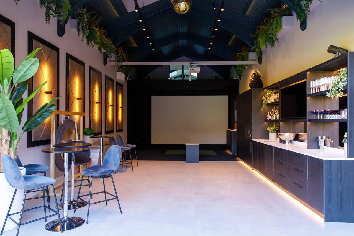 Luxurious entertainment space featuring a golf simulator, ambient lighting, stylish seating, and a sleek bar area. Perfect for relaxing or hosting gatherings. Additional charges apply for use of the golf simulator and bar amenities
