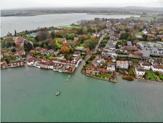 Discover the charm of Bosham Village with this stunning aerial view showcasing its picturesque waterside setting, quaint cottages, and serene landscapes. A perfect destination for exploring coastal beauty and historic attractions.