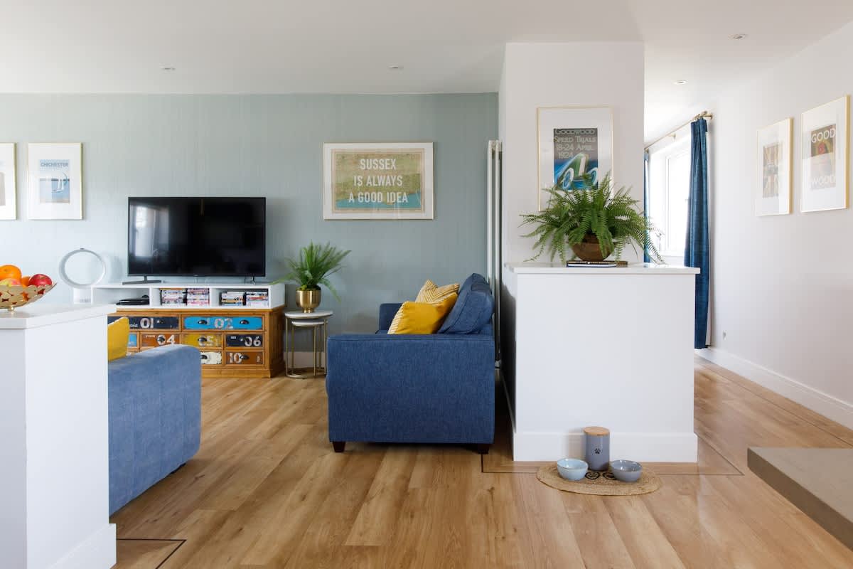 Cedar House: Stylish living space with cozy seating, a flat-screen TV, and vibrant decor. Features open-plan design, natural light, and thoughtful touches, creating a warm and inviting atmosphere for relaxation and entertainment.