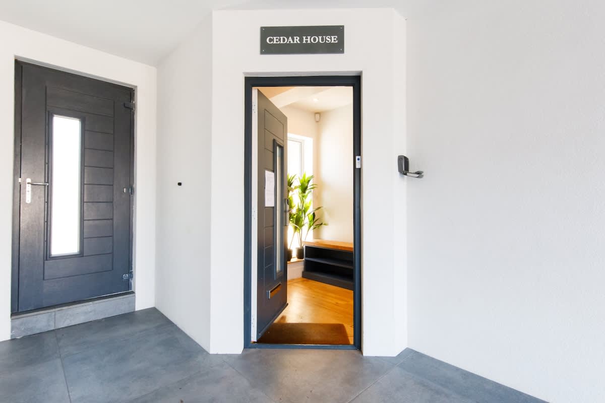 Cedar House: Welcoming entrance with a modern design and natural light. Features a stylish doorway and inviting decor, setting the tone for a relaxing and comfortable stay in this luxurious countryside retreat