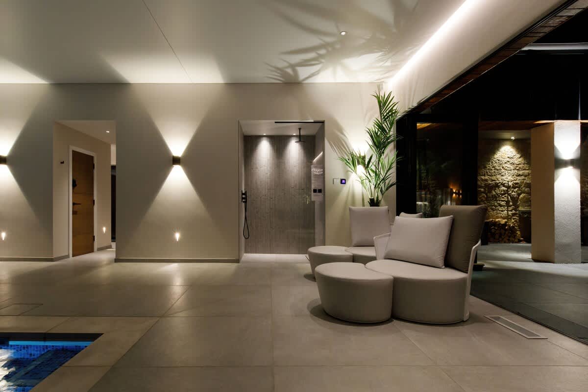 Relax in the sophisticated lounge area of The Cedars spa facility, featuring soft seating and serene lighting. Perfect for unwinding after a swim or sauna session. Access to spa amenities is available with extra charges.