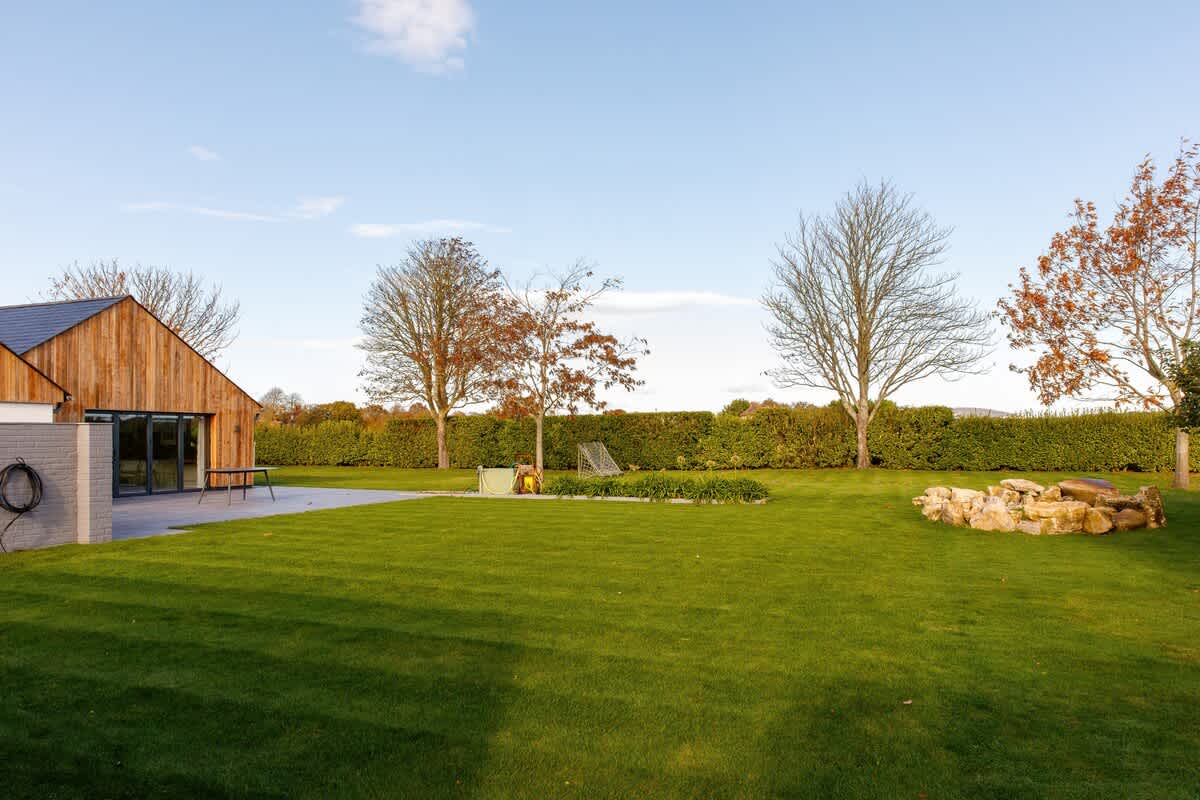 Cedar Lodge: Expansive garden with lush green lawns, a patio area, and scenic views. Perfect for outdoor relaxation, dining, or activities, with charming natural features and plenty of space to unwind in a peaceful countryside setting