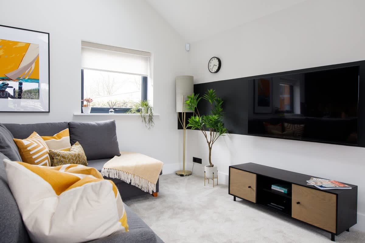 Cedar Lodge: Relax in the cozy living room with a plush sofa, vibrant cushions, and a large smart TV. Thoughtfully designed with stylish decor, natural light, and a peaceful ambiance, perfect for unwinding after a day of exploration.