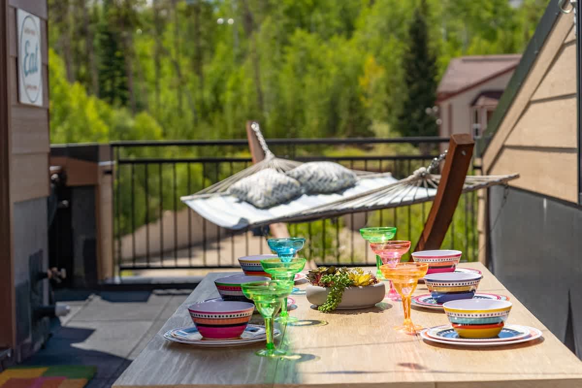 - Savor meals or mocktails at this rainbow accented table with hammock views and fresh pine air
- Plush pillows and bright settings bring playful energy to your rooftop hangout
- Unplug, laugh, and dine together under open skies