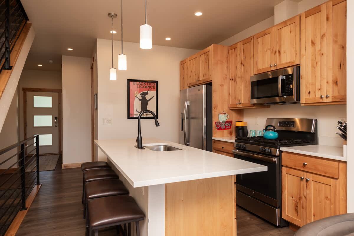 - Cook up something delicious in this full kitchen with natural wood cabinets and sleek appliances
- Oversized island seats three and invites conversation while meals come together
- Chef worthy space designed to feel like home