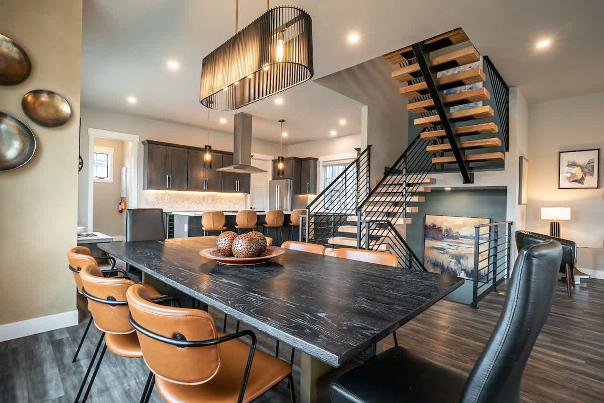 - Bold dining space anchors the open floorplan with a rich wood table and sculptural lighting
- Sleek bar stools and a modern staircase add architectural flair
- Ideal for shared meals, celebrations, and unforgettable evenings