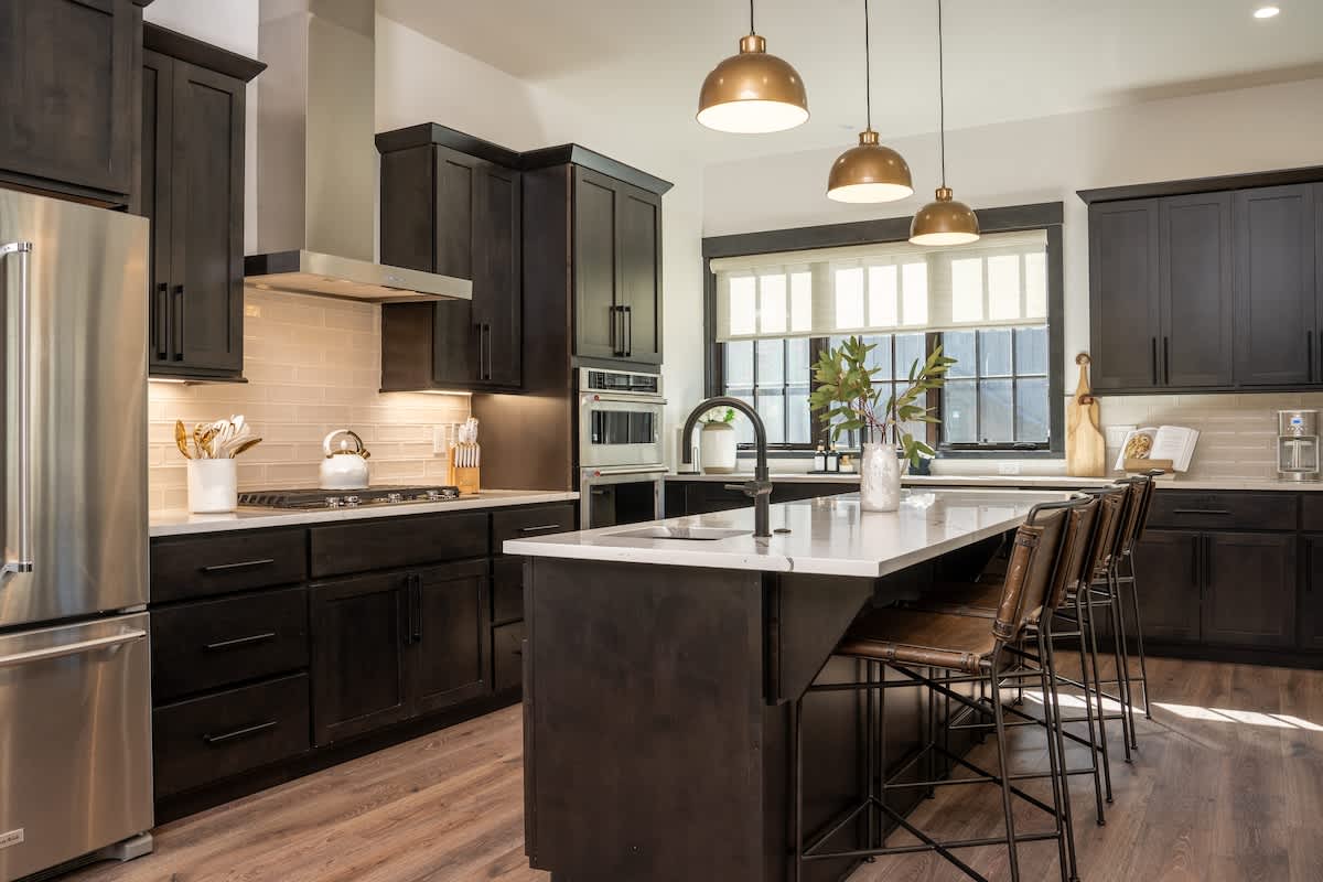 - Cook, gather, and sip in a chef&rsquo;s kitchen filled with sunlight and sleek style
- Dark cabinets, brass pendants, and a wide island set the scene for memorable meals
- From breakfast spreads to wine nights, this space does it all