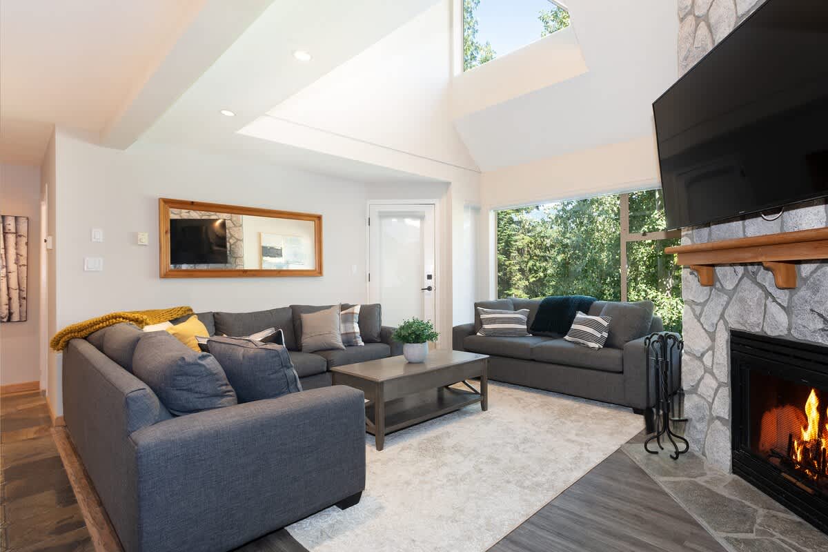 - Bright living room with forest views through wide skylights 
- Plush seating and fireplace create the perfect cozy retreat 
- Relax after skiing surrounded by mountain-inspired décor 