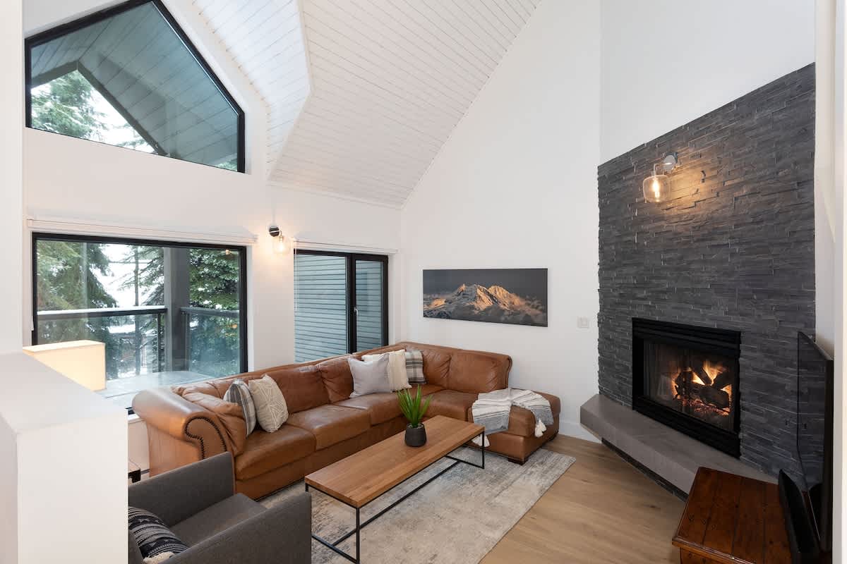 - Inviting living area with vaulted ceilings and panoramic forest views 
- Warm up by the stone fireplace after a day on the slopes 
- Modern alpine design with leather seating and natural light ambiance 