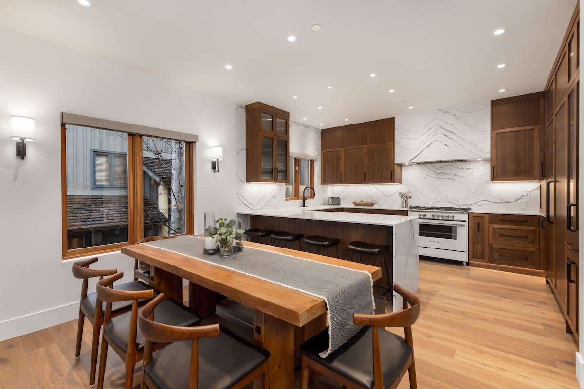 - Open concept kitchen and dining with sleek marble backsplash 
- Wooden cabinetry and high-end appliances for chef-style cooking 
- Long dining table ideal for shared mountain meals 