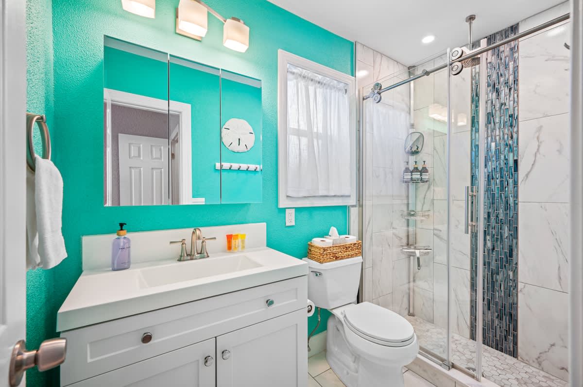 Primary bedroom ensuite featuring a walk-in shower with glass sliding doors. Complimentary shampoo, conditioner, and body wash are included.