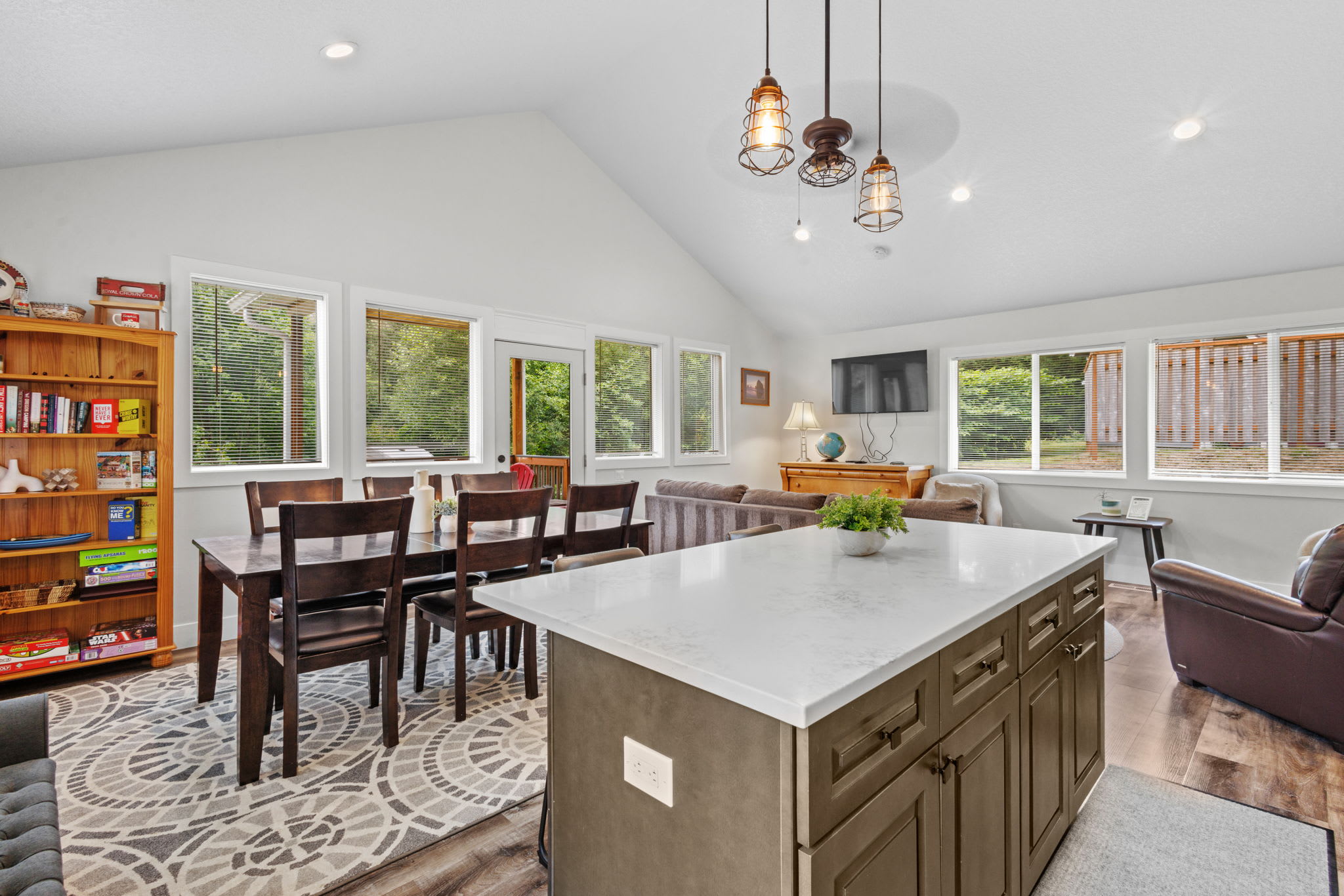 Contemporary kitchen showcasing dark wood cabinets, white quartz countertops, stainless steel refrigerator, range, and microwave, with light wood-look flooring and recessed lighting.