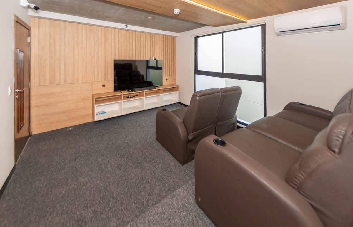 The building has a movie theater, subject to availability. 
It can be booked with the building's concierge and has an additional cost.