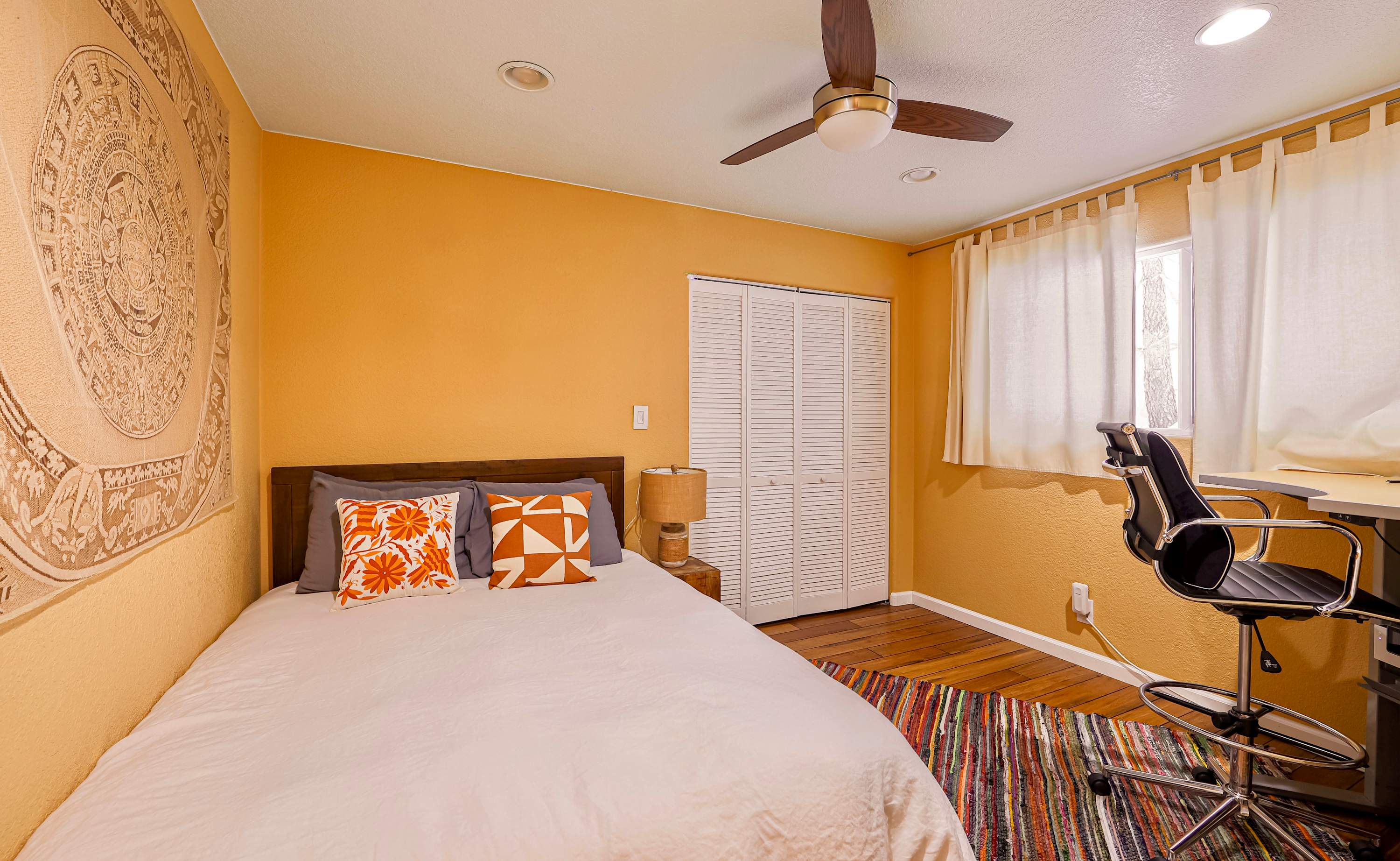 Queen bedroom with a dedicated workspace and ceiling fan​