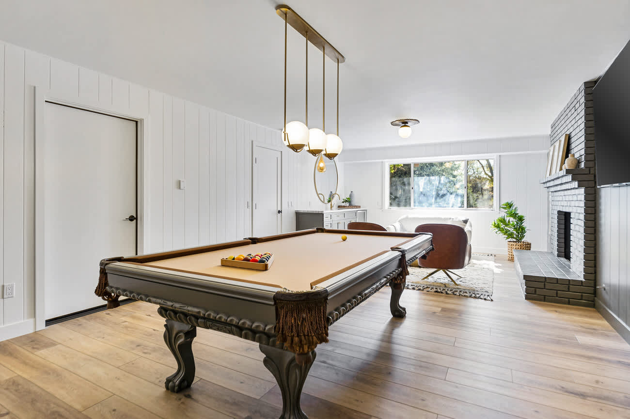 Downstairs game room with billiards, seating area, gas fireplace, and smart TV.