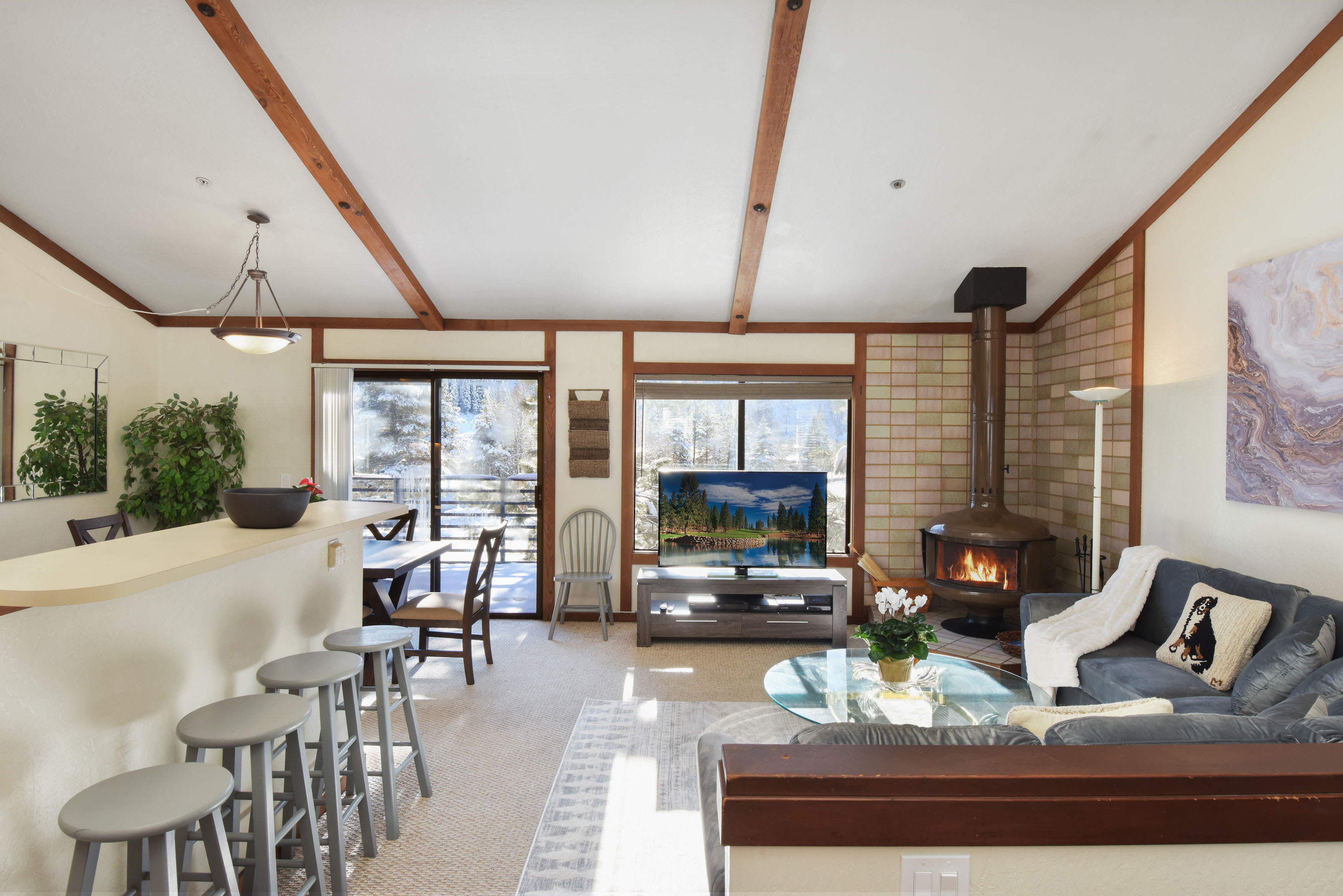 Living room with flat screen TV, wood burning fireplace, balcony access and high ceilings