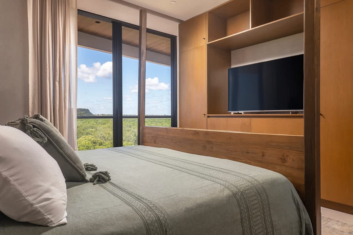 Bedroom with a tranquil jungle view, featuring a luxurious king-size bed and TV