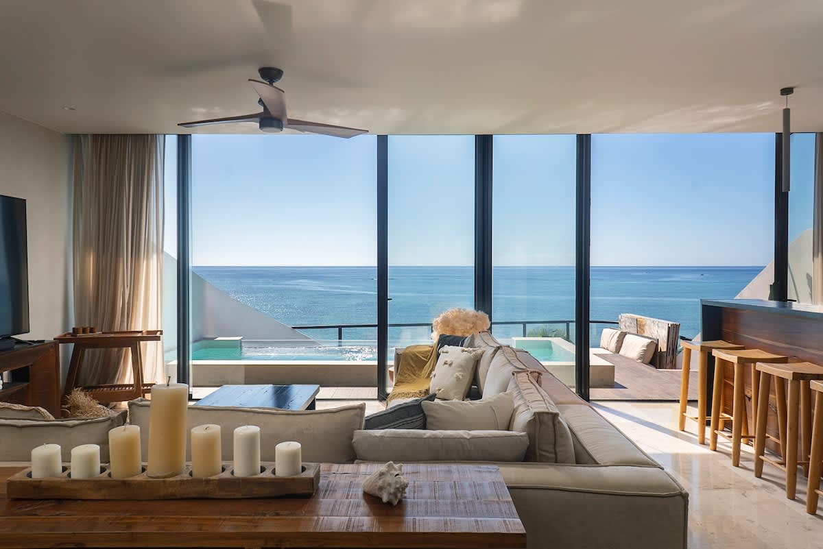 A beautifully designed, modern living room featuring a large TV and offering stunning views of the beach