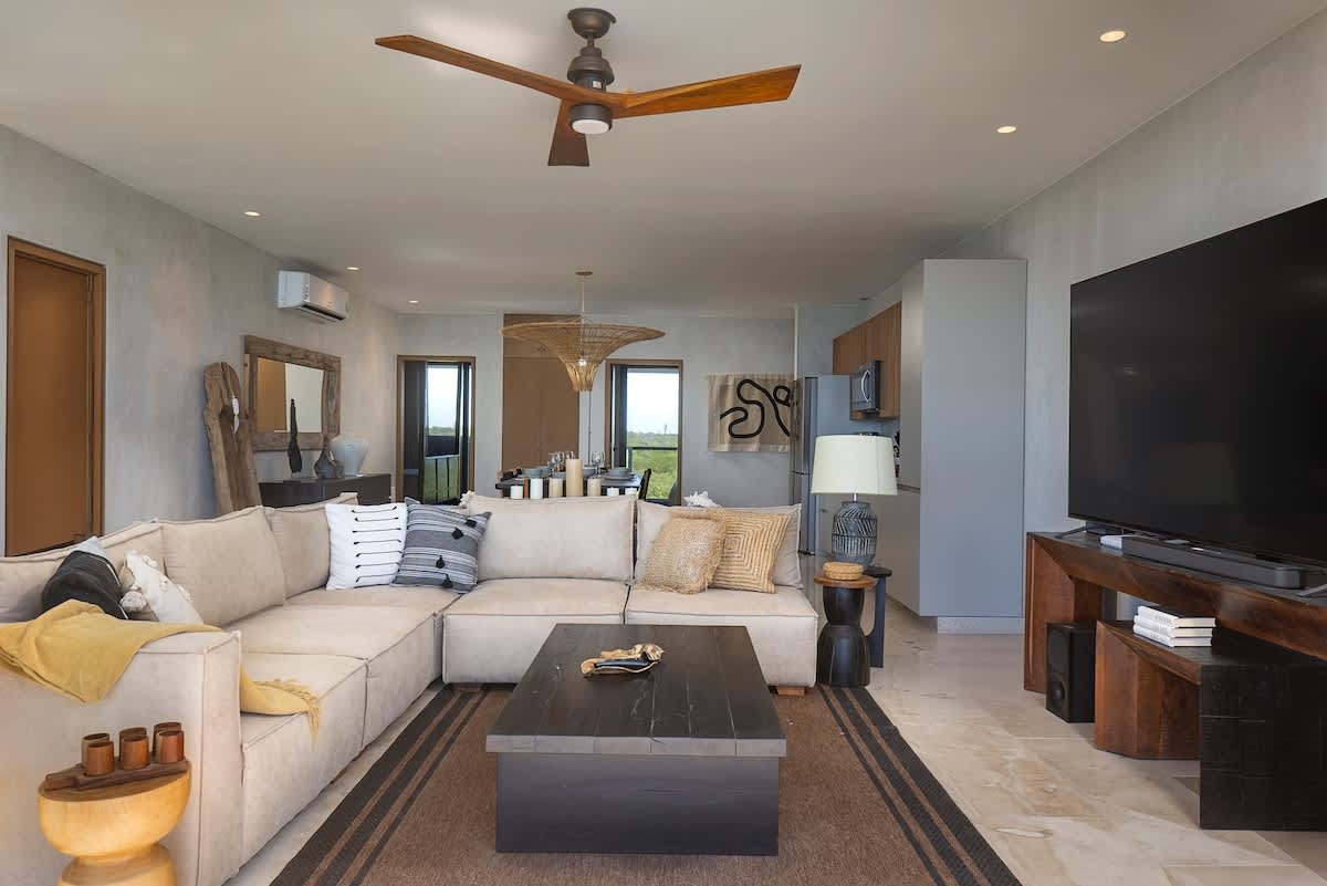 A beautifully designed, modern living room featuring a large TV and offering stunning views of the beach