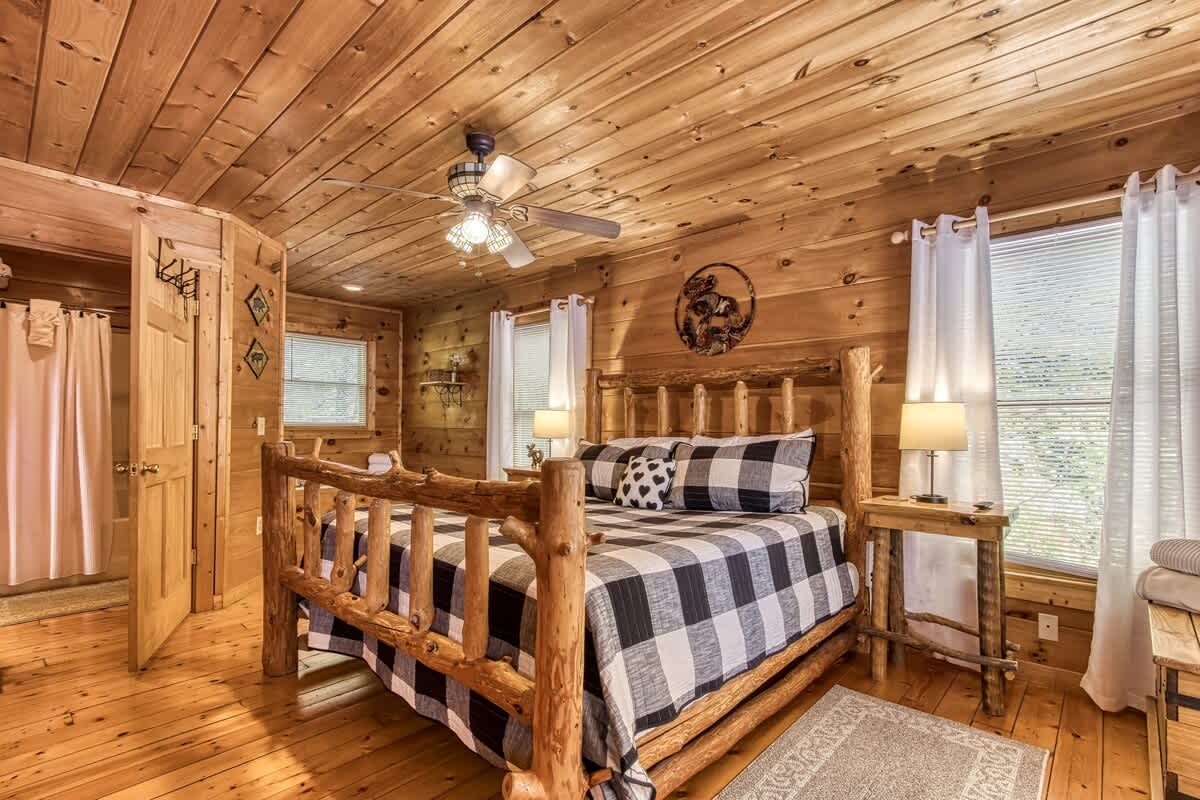 Primary bedroom: Charming wooden decor, cozy bed, and bright windows invite your relaxation!