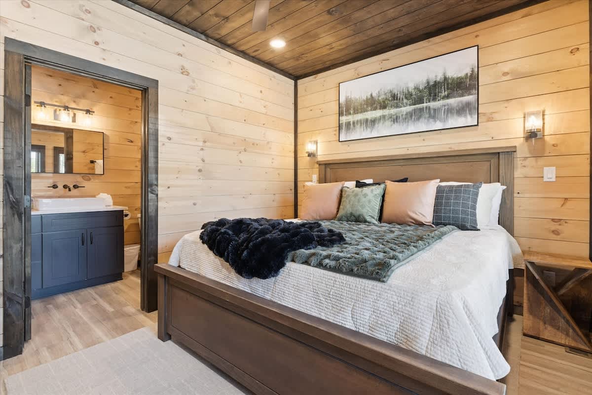 Charming Bedroom: Rustic wooden walls, plush bedding, and a serene bath retreat await you!