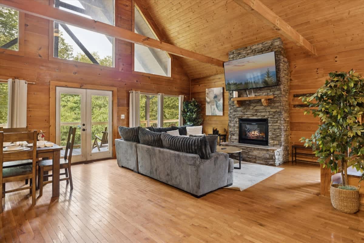 Living Room: Expansive windows invite nature in, perfect for unforgettable gatherings by the fire!