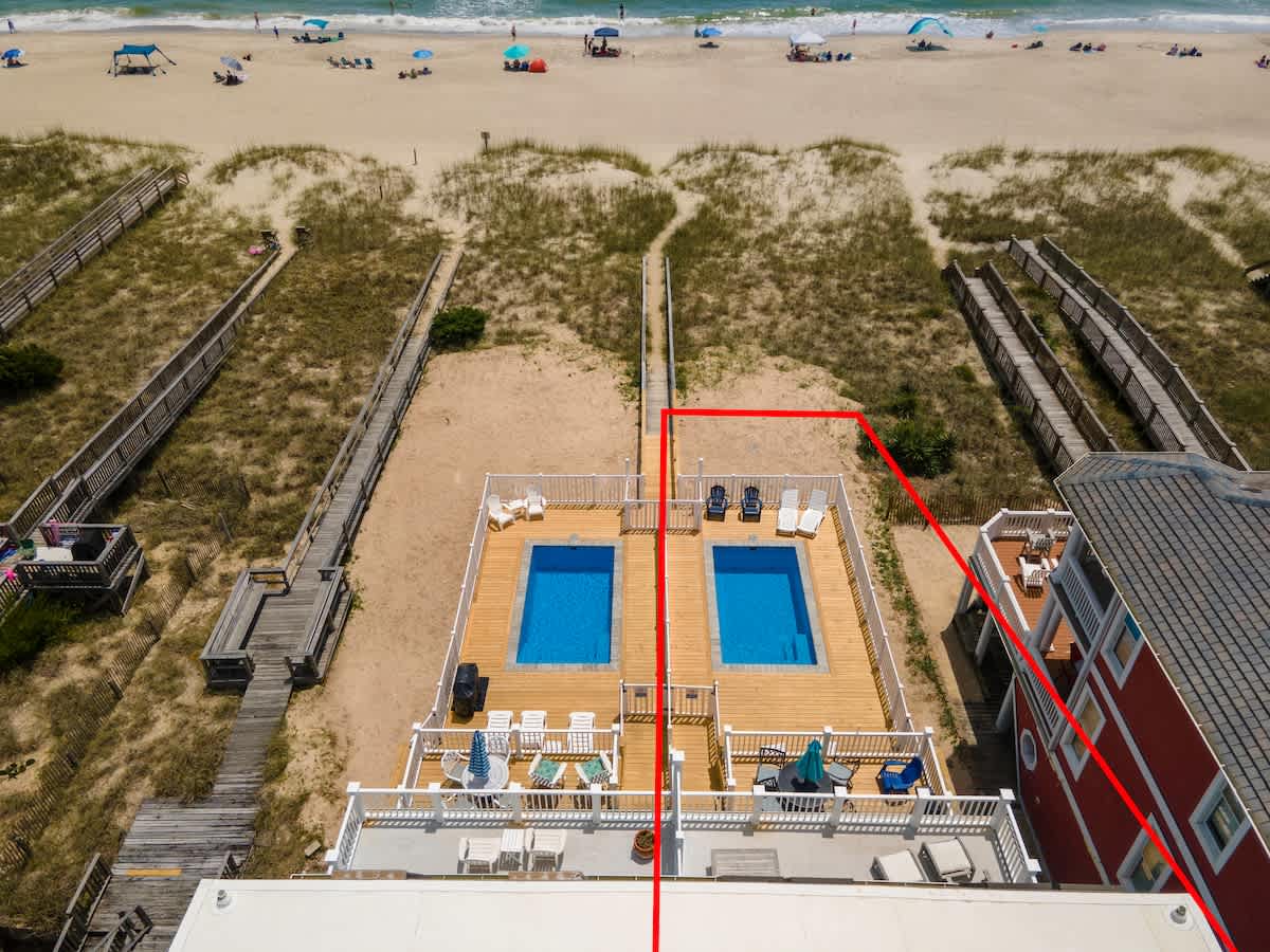 Outdoor living at the back of the home with deck, pool, and beach views.
