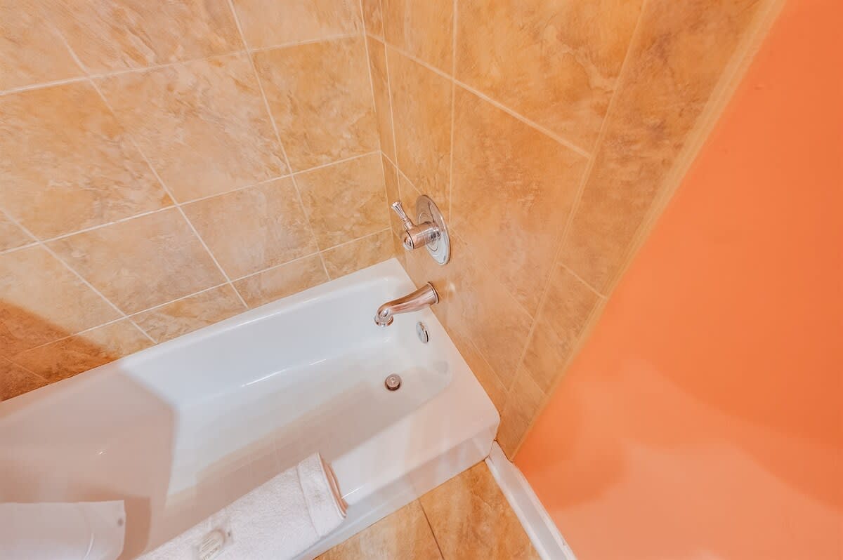- Relaxing bathtub with warm tile accents, perfect for unwinding after a long day - Spacious and inviting, offering a comfortable soak whenever you need it - Clean and refreshing spot to refresh and recharge during your stay