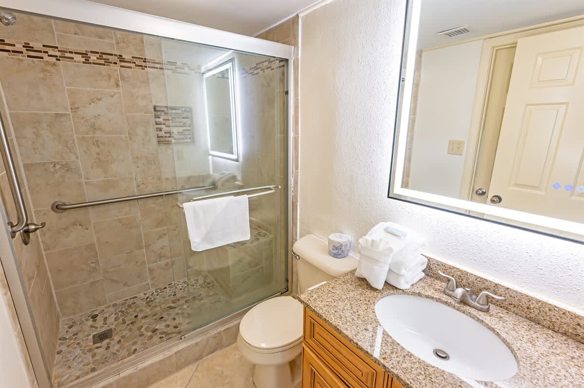 - Bathroom with walk-in shower featuring modern tile and glass door   - Granite vanity and bright lighting create a fresh design   - Perfect space for refreshing after beach days and adventures