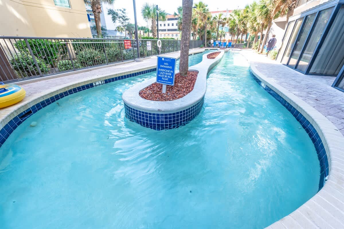 - Winding lazy river pool designed for endless floating fun   - Outdoor setting with palm trees and seating along the path   - Perfect way to relax and enjoy sunshine during vacation