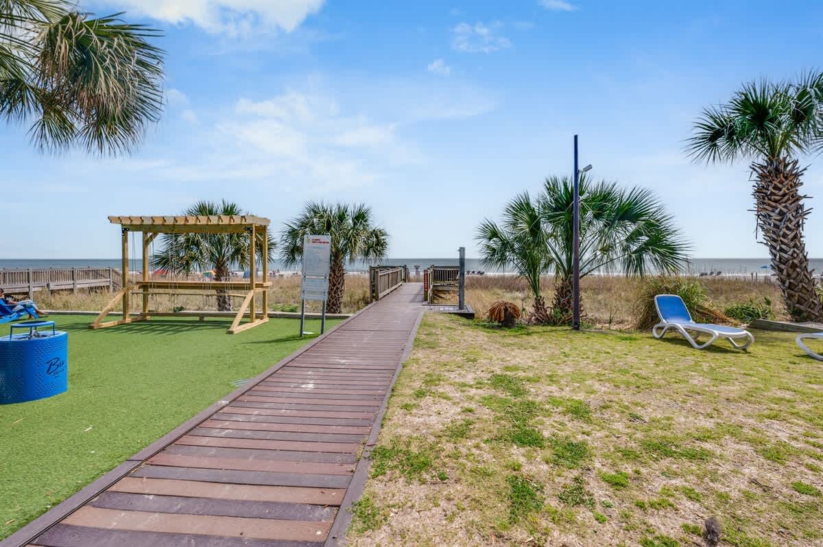 - Walkway leading directly to the sandy beach   - Outdoor seating and swings along the path   - Easy beach access from the condo grounds