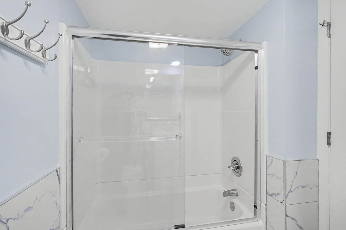 Step into your beautifully appointed bathroom featuring a spacious glass-enclosed shower with elegant marble-look tiling and chrome fixtures for your refreshing moments.